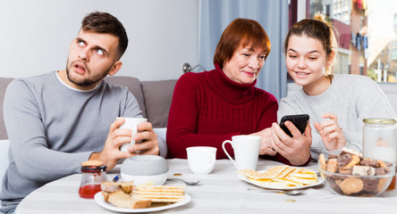 Man bored while wife and mother looking at phones