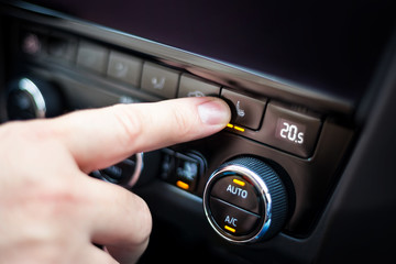 Hand pressing the button for heated seats in the car