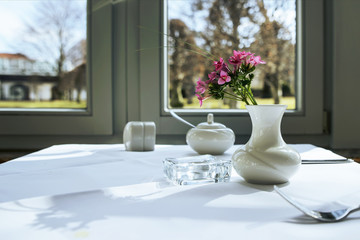 Morning table setting for breakfast from white tableware by the window with an interesting view.