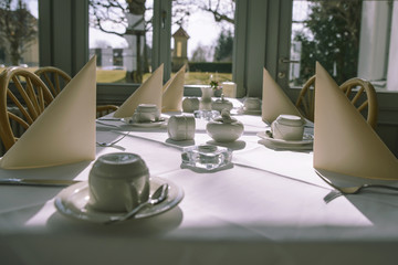 Morning table setting for breakfast from white tableware by the window with an interesting view.