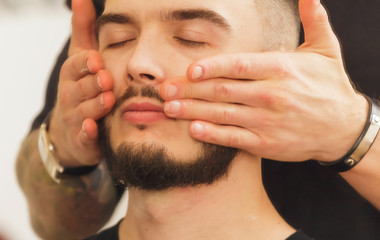 Obraz premium A young hairdresser who does a haircut and styling an attractive man in a hair salon