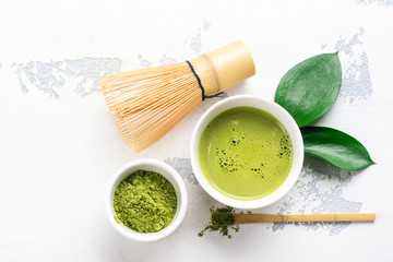 Green matcha tea drink and tea accessories on white background