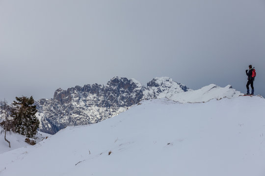 Man on snowy slopes that admires the Dolomite peaks, Col Visentin, Belluno, Italy