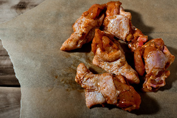 Raw marinated chicken wings on parchment -  ready for cooking.