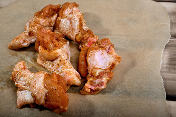 Raw marinated chicken wings on parchment -  ready for cooking.