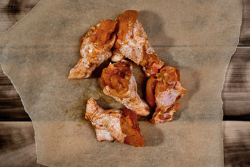 Raw marinated chicken wings on parchment -  ready for cooking.
