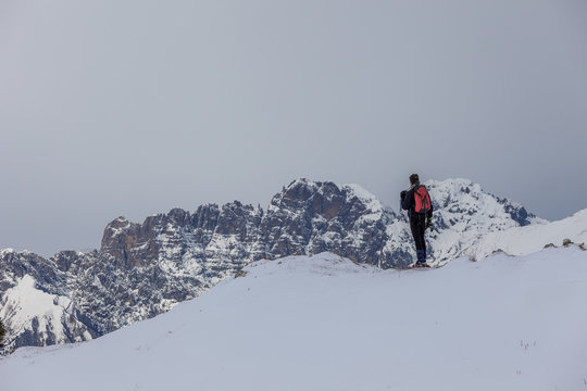 Man on snowy crest that admires the Dolomite peaks, Col Visentin, Belluno, Italy