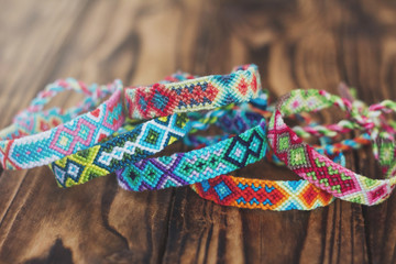 colored handmade friendship bracelets on wooden background