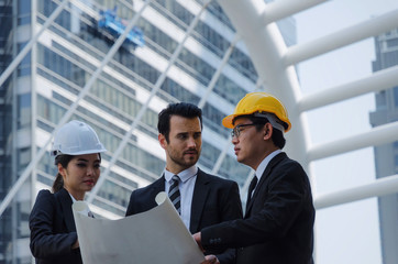 group of business or engineer woman and man with safety helmet and blueprint planning at the building and checking their work in modern city, planning start up new project, successful concept