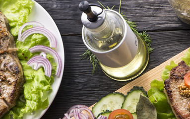 Fried veal steak and lettuce leaf, spices. On a wooden table