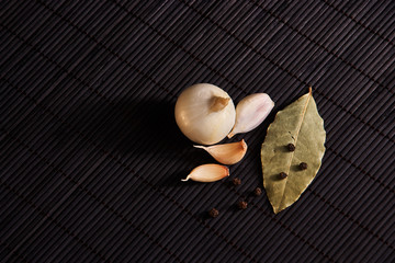 onion, garlic, black pepper and bay leaf on a black background