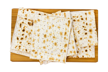 An overhead photo of Jewish matza on the wooden chopping board, leavened bread isolated on white background. The photo from above of the matzah for jewish passover. Selective soft focus.