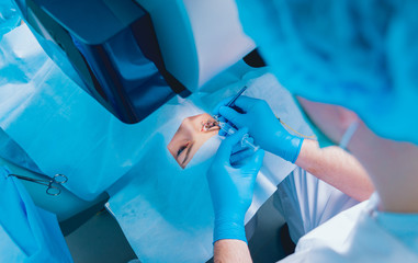 Laser vision correction. A patient and team of surgeons in the operating room during ophthalmic...