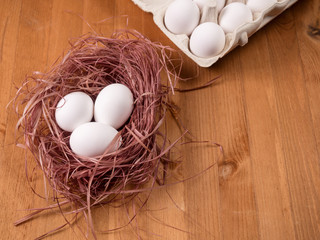 Nest with white eggs and packing for eggs on a wooden background