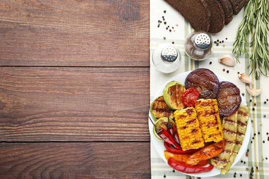 Grilled vegetable in plate with salt, pepper, bread and rosemary on wooden table