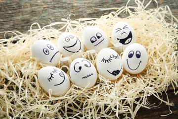Foto op Canvas Eggs with funny faces in nest on wooden table © 5second