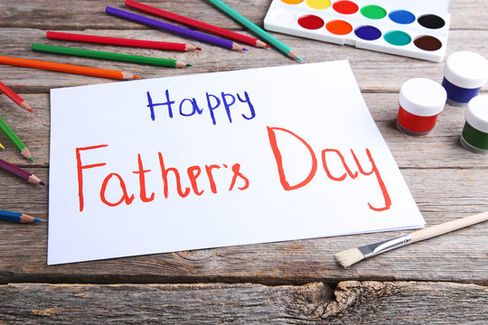 Happy fathers day written on white paper on wooden table
