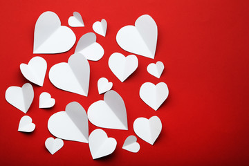 White paper hearts on red background