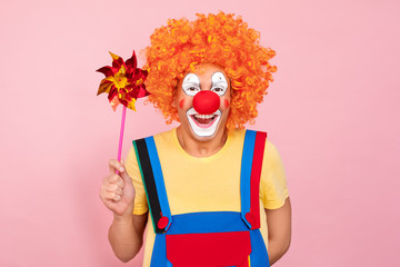 Man in a red wig, overalls and makeup holding kids toy