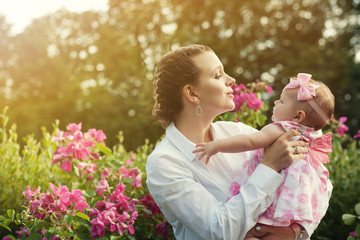 a young beautiful mother holding a small daughter in her arms and hugging her