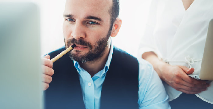 Bearded young businessman working on modern office. Consultant man thinking looking in monitor computer. Manager coworking on workplace, discussio startup project concept in studio with colleague