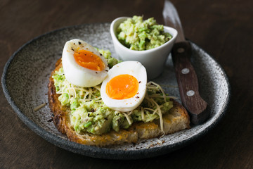 Toast with mashed avocado, egg and cheese on dark background. Closeup view. Healthy eating, healthy snack, lunch or breakfast