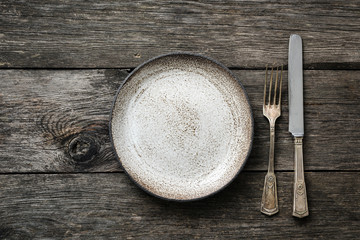 Table setting with vintage silverware or cutlery and empty plate on rustic wood. Top view with copy...