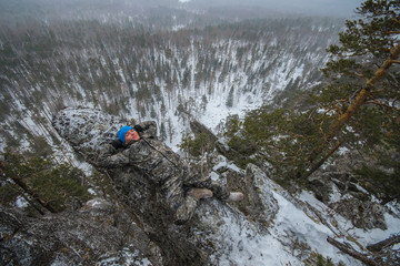 Man hiker have rest at mountain top, relax lying on rock.