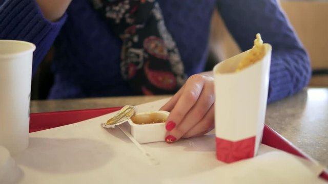 a woman eats fast food in a cafe. hands close-up