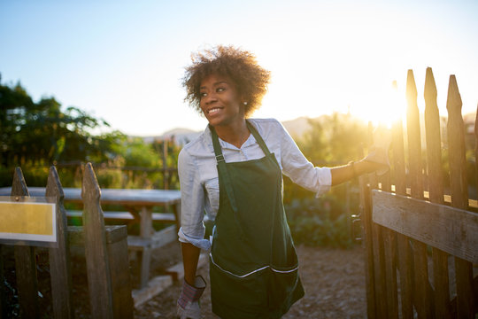 African American Female Gardener Walking Out Of Community Urban Garden At End Of Day