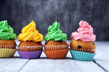 Tasty cupcakes on wooden background. Birthday cupcake in rainbow colors