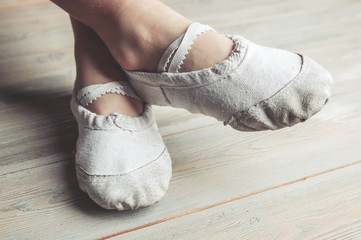 A little dancer. Legs of a girl in ballet slippers on a wooden floor