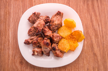 Mutton shish kebabswith baked potato on the plate on wooden table