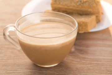 Traditional Russian baked honey cake, sliced on white plate and glass cup with coffee or cocoa drink