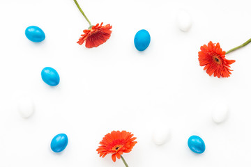 Blue easter eggs and orange flowers on white background. Flat lay, top view