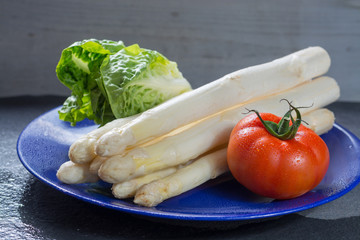 White raw big Dutch asparagus ready to cook, red tomato and green lettuce close up