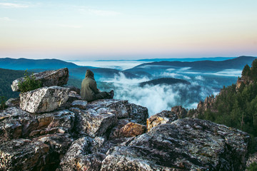 A man hiker sitting back on rock on mountain peak and enjoy to see beautiful landscape view at summer morning.