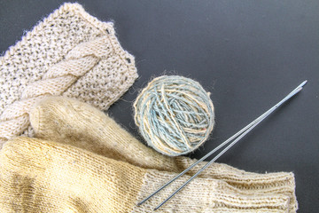 A ball of wool with knitting needles and socks on a gray table. Needlework.