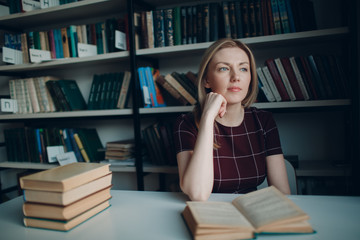 Young beautiful blond student girl with books thinking
