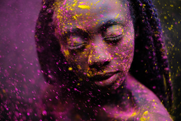 African woman with colourful powder on her face and body.