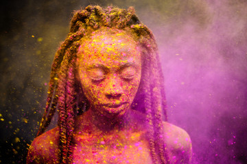 African woman with colourful powder on her face and body.