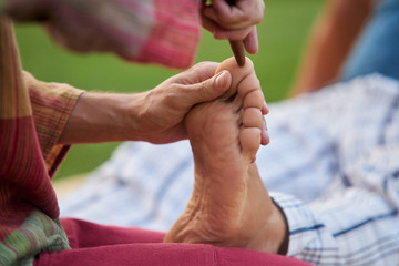 Thai foot massage training course. Wooden stick touching foot finger, close up.