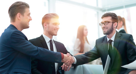 Partners concluding deal and shaking hands in the presence of team members