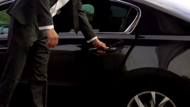 Personal driver is opening the car door for his client, hotel transfer services