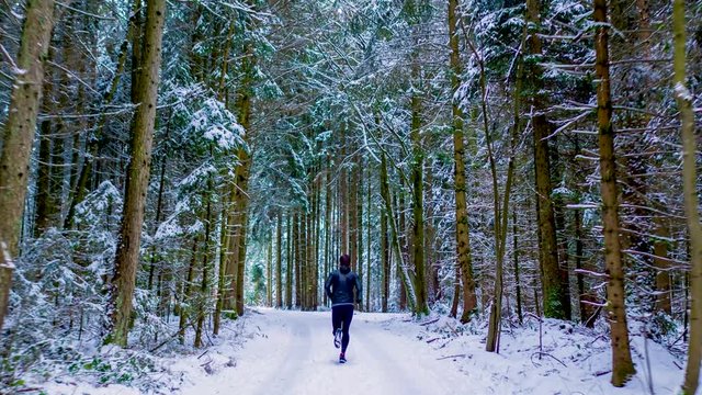 Man running in the forest in deep winter