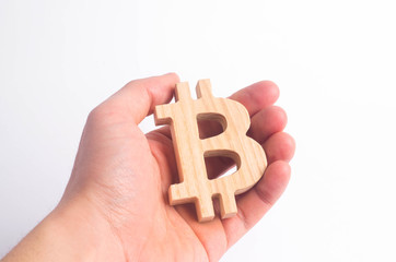 Hand holds a wooden Bitcoin on a white. Crypto currency, blocking technology. The collapse and rise in the cost of bitcoin. Mining farms, miners, stock exchange crypts. Decentralized money.