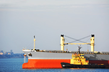 Tugboat assisting bulk cargo ship
