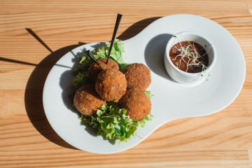 closeup of plate with spanish croquettes served with salad and sauce