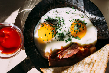 Fried eggs, bacon, tomatoes at toast. Classic breakfast food in iron pan