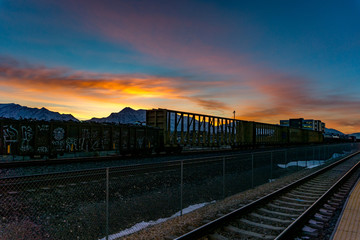 Fototapeta na wymiar Railroad tracks and cars during a stunning sunrise